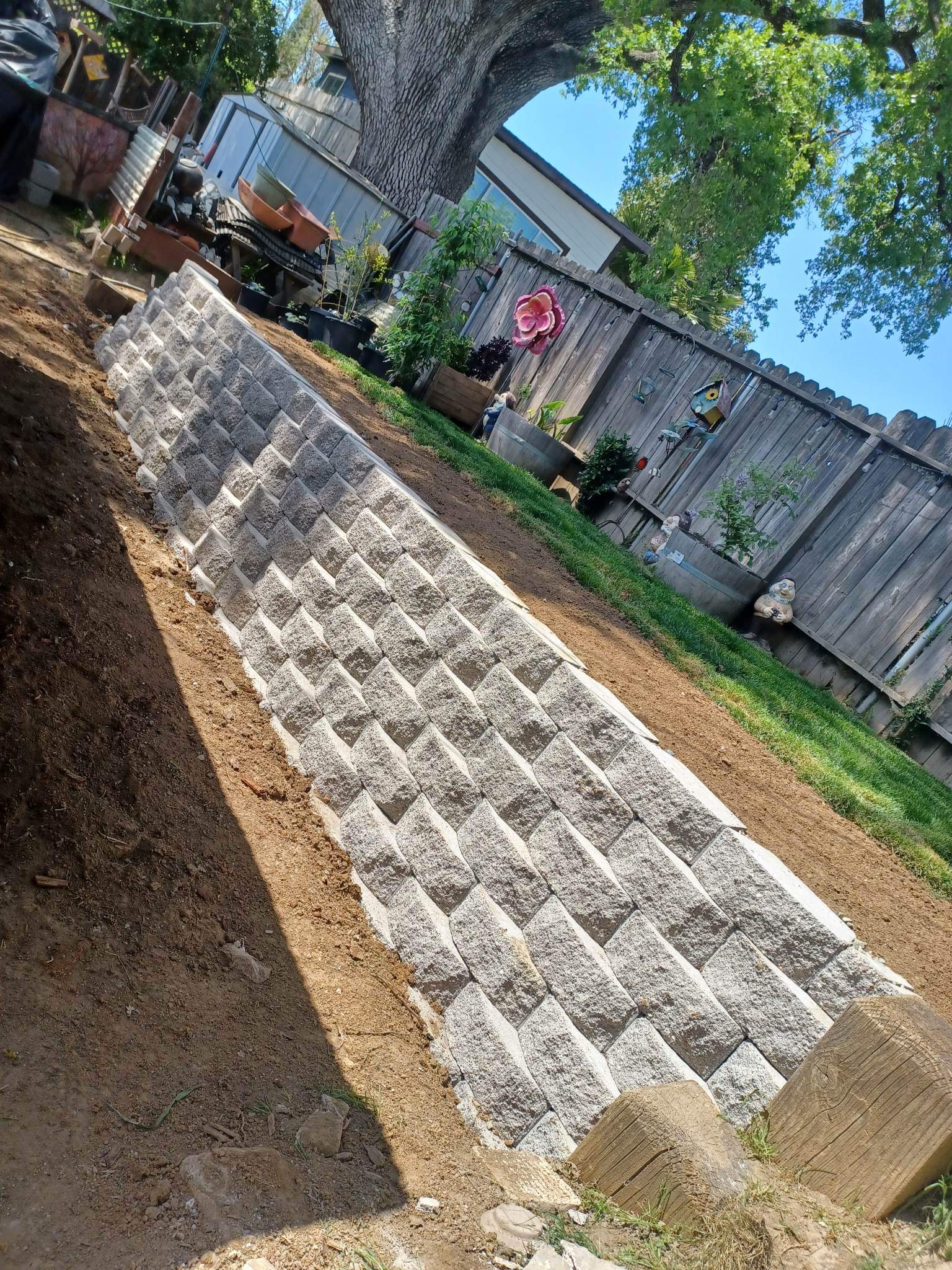 Long checkered-block retaining wall built along a sloped backyard
