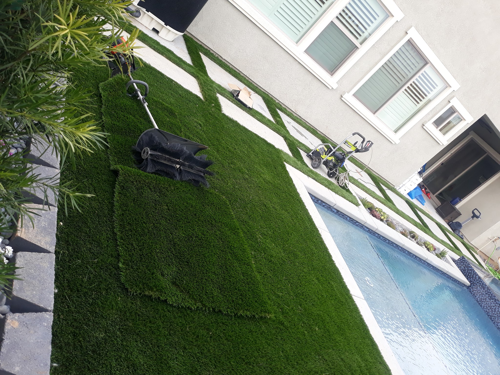Fresh artificial turf installation next to a pool deck