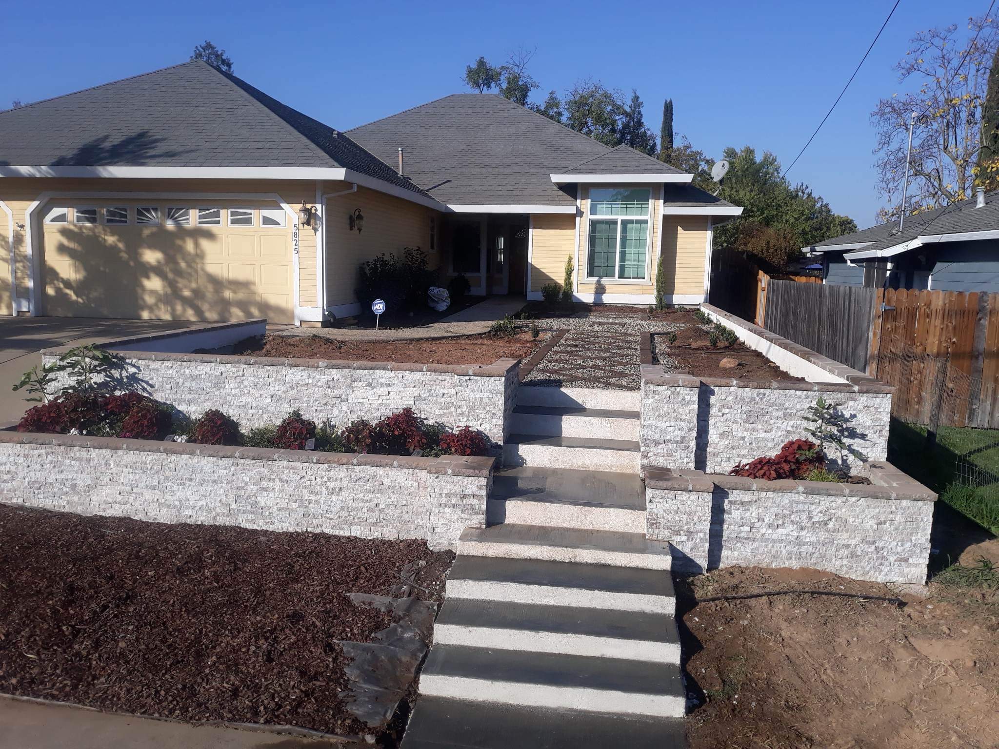 Newly finished stacked stone retaining walls framing a front walkway