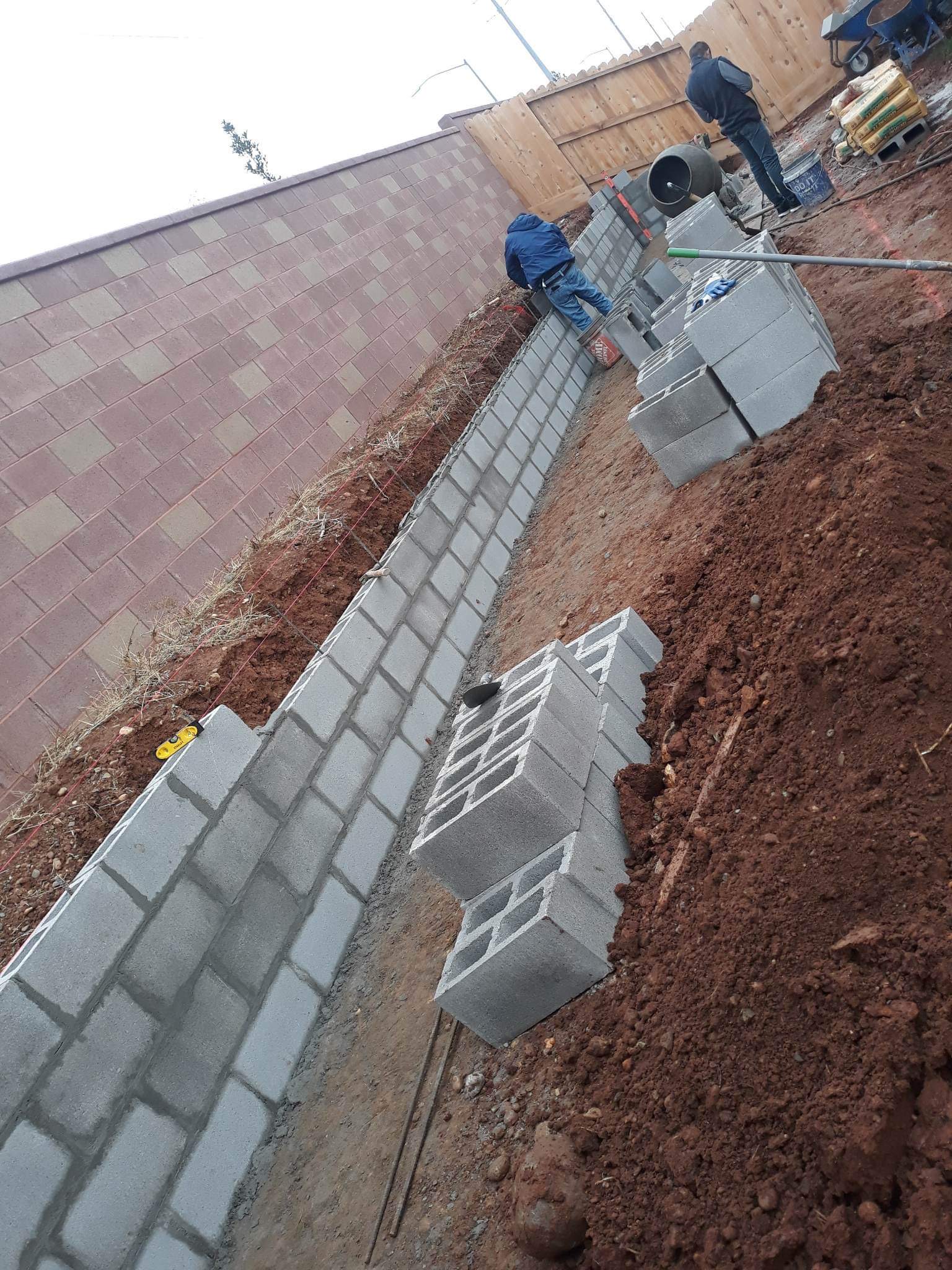 Crew building a concrete block retaining wall on a sloped job site